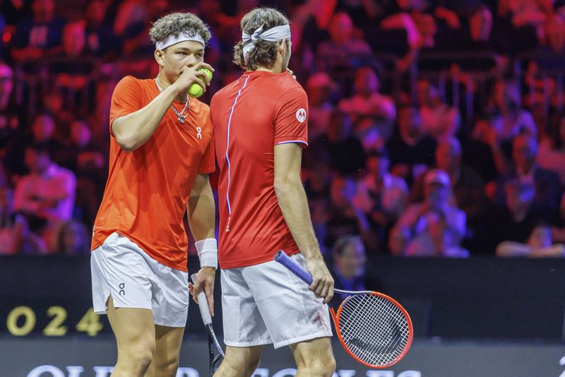 Team World's Ben Shelton, left, and Taylor Fritz confer during a doubles match against Team Europe's Carlos Alcaraz and Alexander Zverev on the first day of the Laver Cup tennis tournament at the Uber arena in Berlin, Germany, Friday, Sept. 20, 2024. (Andreas Gora/dpa via AP)