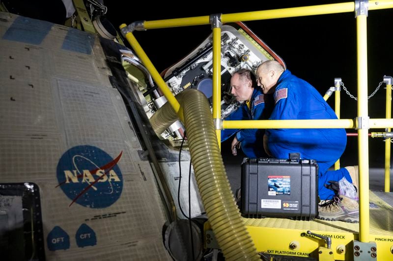 NASA astronauts Mike Fincke, left, and Scott Tingle look inside NASA's Boeing Crew Flight Test Starliner spacecraft after the empty capsule landed at White Sands Missile Range's Space Harbor, Friday, Sept. 6, 2024, in New Mexico. (Aubrey Gemignani/NASA via AP)