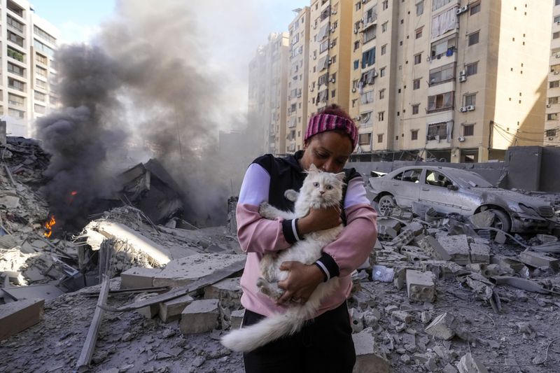 A woman holds her cat in front of a destroyed building at the site of an Israeli airstrike in Dahiyeh, Beirut, Lebanon, Wednesday, Oct. 2, 2024. (AP Photo/Hassan Ammar)