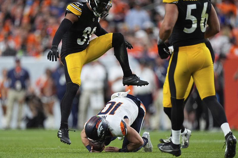 Denver Broncos quarterback Bo Nix (10) falls after a short gain as Pittsburgh Steelers safety Minkah Fitzpatrick (39) leaped over him during the second half of an NFL football game, Sunday, Sept. 15, 2024, in Denver. (AP Photo/David Zalubowski)