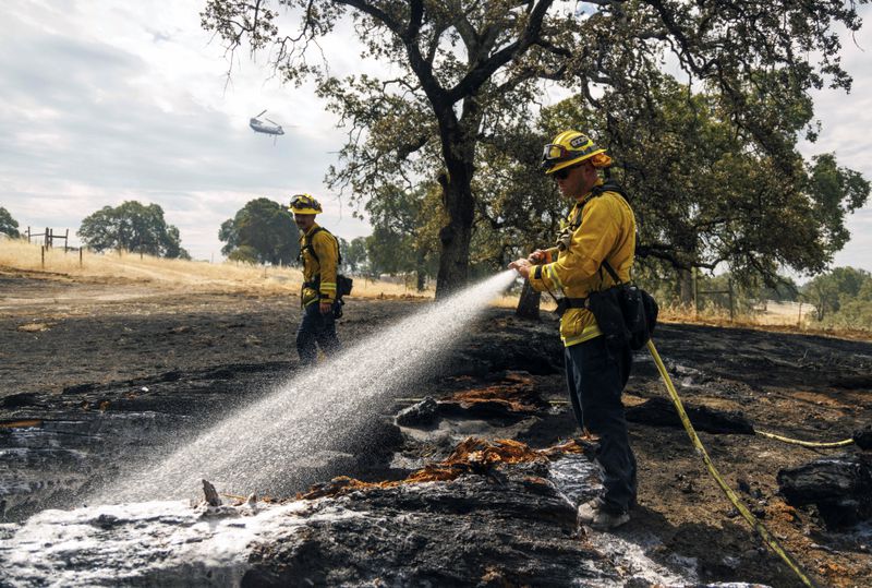 Firefighters mop up as the Apache Fire burns in Palermo, Calif., on Tuesday, Jun. 25, 2024. According to Cal Fire, more than a dozen new fires sparked by lightning. (AP Photo/Ethan Swope)