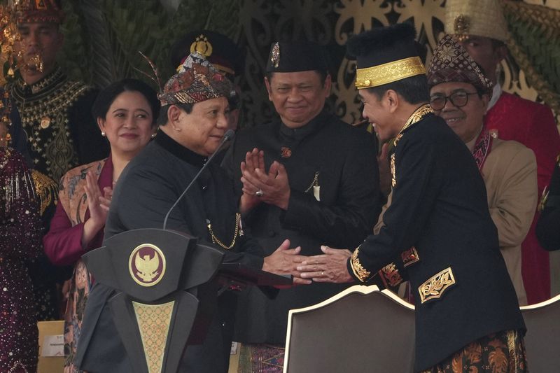 Indonesian President Joko Widodo, right, shakes hands with Defense Minister and president-elect Prabowo Subianto during the ceremony marking Indonesia's 79th anniversary of independence at the new presidential palace in its future capital of Nusantara, a city still under construction on the island of Borneo, Saturday, Aug. 17, 2024. (AP Photo/Achmad Ibrahim)