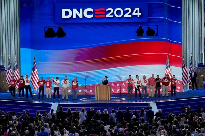 Benjamin C. Ingman, center, former student of Democratic vice presidential candidate Minnesota Gov. Tim Walz, is joined on stage by former members of the Mankato West High School football team during the Democratic National Convention Wednesday, Aug. 21, 2024, in Chicago. (AP Photo/J. Scott Applewhite)