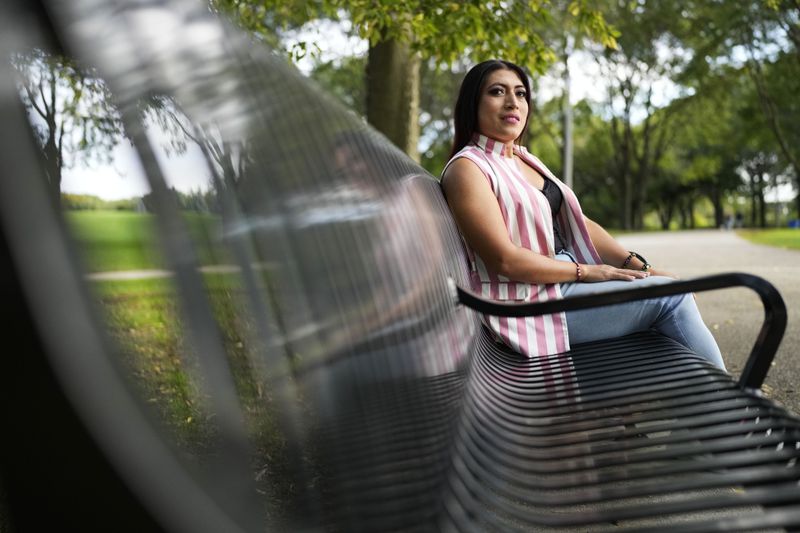 Julieth Luna Garcia, a transgender woman from El Salvador, sits on a bench as she looks at trees at Horner Park in Chicago, Monday, Sept. 30, 2024. (AP Photo/Nam Y. Huh)