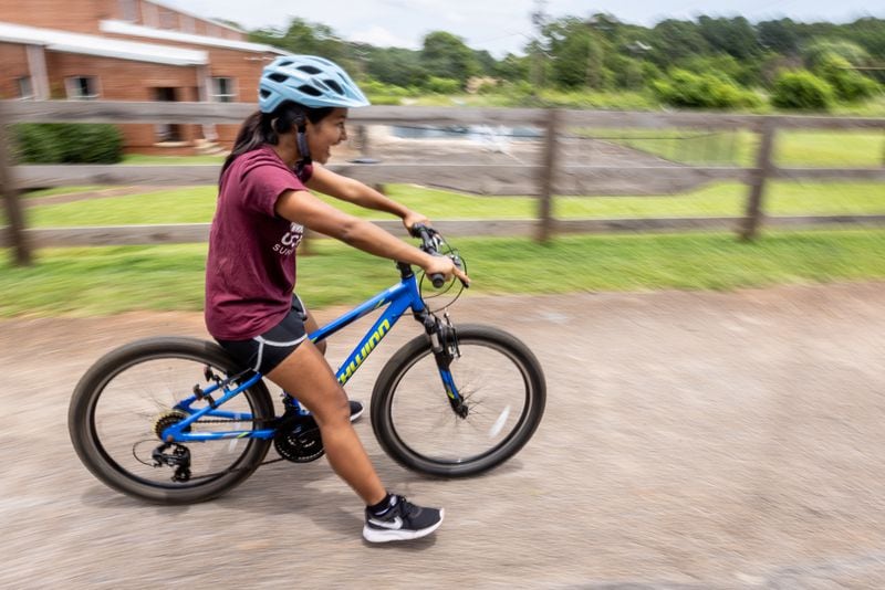  Mang Bor Cin glides down a shallow hill with her feet off the ground during Mang Bor Cin's first bike riding lesson in Decatur Saturday. July 23, 2023.  (Steve Schaefer/steve.schaefer@ajc.com)