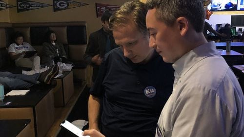 Ben Ku looks over local election results with campaign volunteer Charley Levinson during a watch party Tuesday night at Crowne Sports Bar. ARLINDA SMITH BROADY / ABROADY@AJC.COM