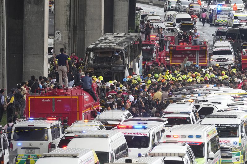 Rescuers gather at the site of a bus that caught fire, carrying young students with their teachers, in suburban Bangkok, Tuesday, Oct. 1, 2024. (AP Photo/Sakchai Lalit)