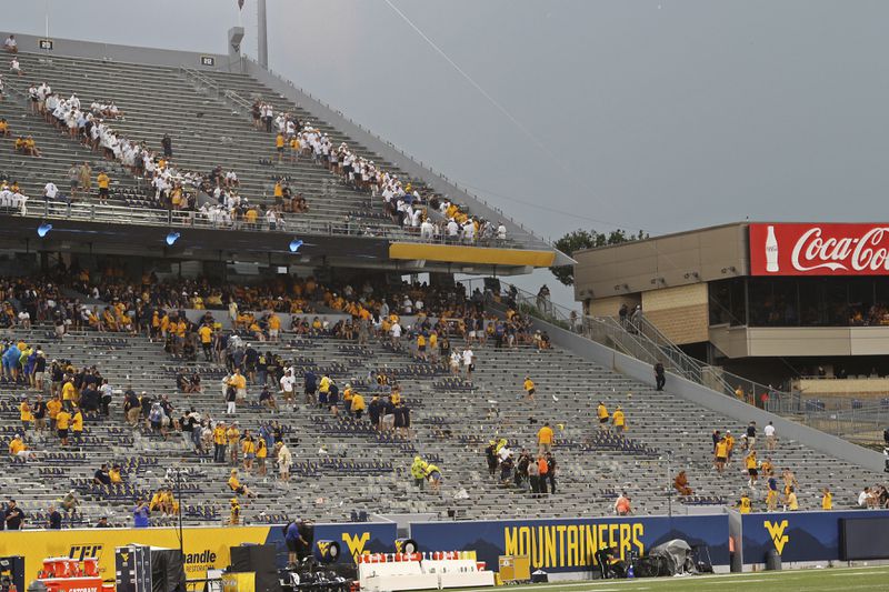 Fans clear the stands of Milan Puskar Stadium during a weather delay in the first half of an NCAA college football game between Penn State and West Virginia in Morgantown, W.Va., Saturday, Aug. 31, 2024. (AP Photo/Kathleen Batten)