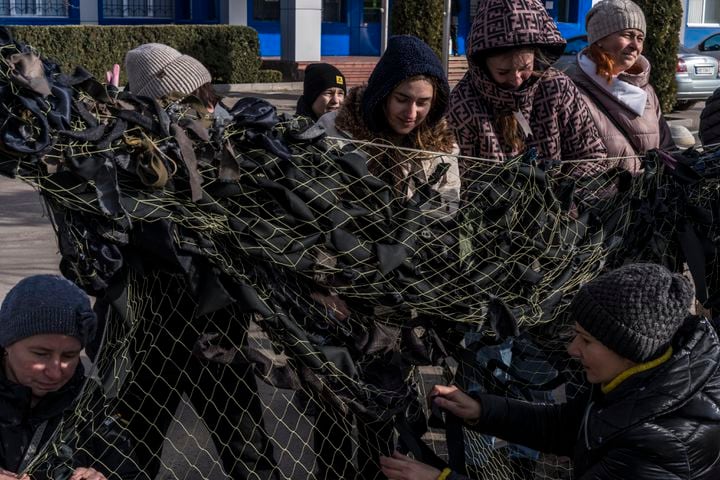 Volunteers hand-tie camouflage netting for use by the Ukrainian military in Kalynivka, Feb. 26, 2022. (Brendan Hoffman/The New York Times)