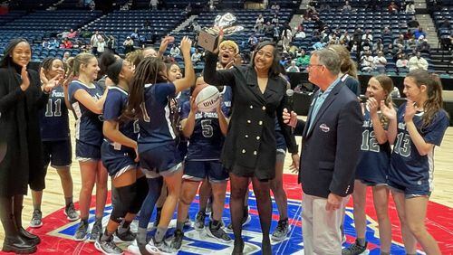 Head coach Aisha Kennedy and the St. Francis players celebrate with the trophy after their 74-71 overtime victory over Galloway in the Class A Division I girls basketball championship game at the Macon Coliseum on March 9, 2024.