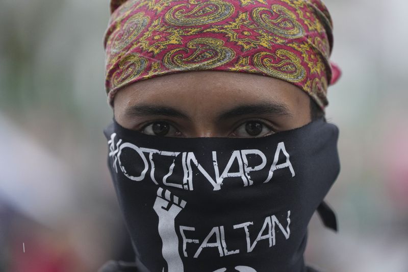 A masked youth takes part in a demonstration marking the 10-year anniversary of the disappearance of 43 students from an Ayotzinapa rural teacher's college, in Mexico City, Thursday, Sept. 26, 2024. (AP Photo/Fernando Llano)