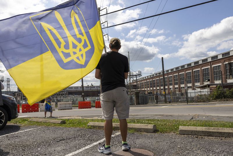 Maxim Trushin, a native of Ukraine, waves a flag before President of Ukraine Volodymyr Zelenskyy's motorcade arrives at the Scranton Army Ammunition Plant in Scranton on Sunday, Sept. 22, 2024. (AP Photo/Laurence Kesterson)