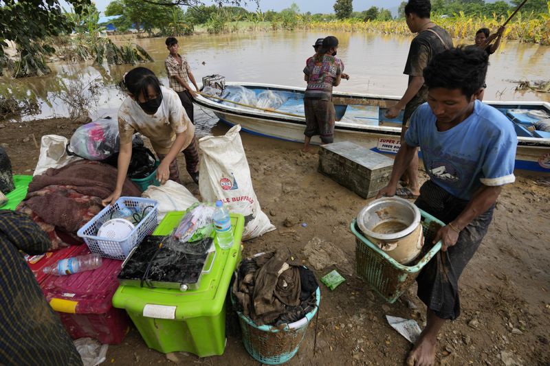 Local residents carry their belongings along a flooded road, in Naypyitaw, Myanmar, Tuesday, Sept. 17, 2024. (AP Photo/Aung Shine Oo)