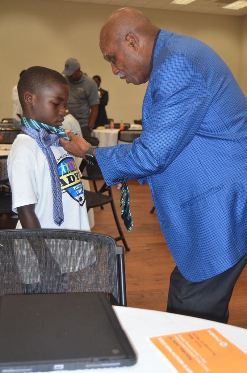 Ivon Hall, 8, left, receives instruction on tying a necktie from former Albany Mayor Willie Adams. (Photo Courtesy of Alan Mauldin)