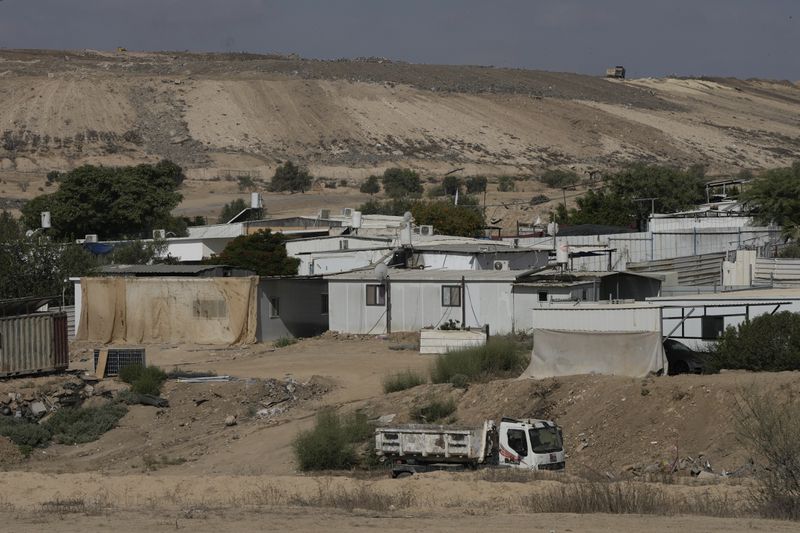 Houses of Bedouin families stand on area in the Negev desert next to a place where relatives and friends of Qaid Farhan Alkadi, 52, who was held hostage by Hamas militants in Gaza Strip, wait for his arrival in the Khirbet Karkur village, near Rahat, southern Israel, Wednesday, Aug. 28, 2024. (AP Photo/Mahmoud Illean)