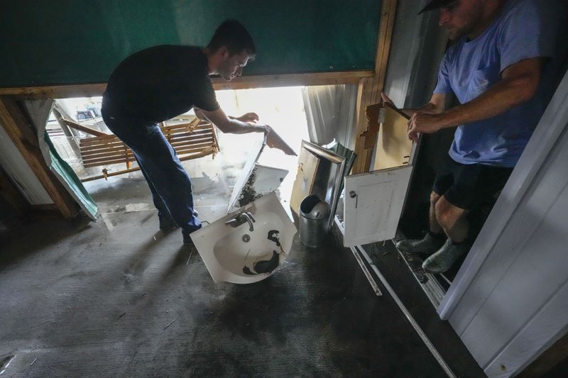 Jansen Pellegrin, right, and his brother-in-law Allen McCoy gut a bathroom as they help clean out their family's camp, which took on a storm surge, in the aftermath of Hurricane Francine, in Cocodrie, La., Thursday, Sept. 12, 2024. (AP Photo/Gerald Herbert)