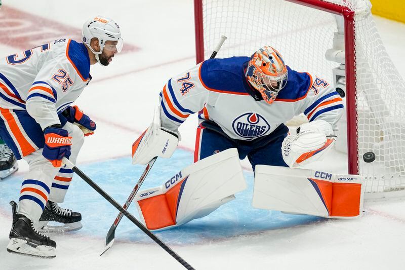 Edmonton Oilers defenseman Darnell Nurse (25) and goaltender Stuart Skinner (74) eye the puck on a shot by the Dallas Stars during overtime in Game 1 of the NHL hockey Western Conference Stanley Cup playoff finals, Thursday, May 23, 2024, in Dallas. (AP Photo/Tony Gutierrez)