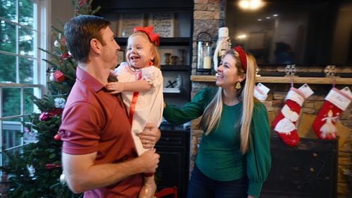 Andi and Ryan Mahoney play with their daughter Emmie at their home in Milton. Emmie was born without kidneys and was given little chance of survival. Now she is considered a medical marvel and is spending her first Christmas at home. (Hyosub Shin / Hyosub.Shin@ajc.com)