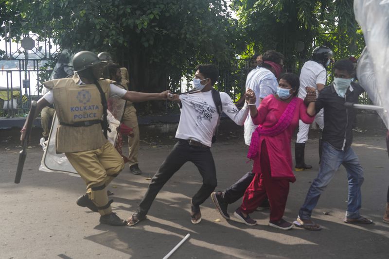 A policeman grabs protesters against the rape and murder of a resident doctor at a government hospital earlier this month, in Kolkata, India, Tuesday, Aug. 27, 2024. (AP Photo/Bikas Das)