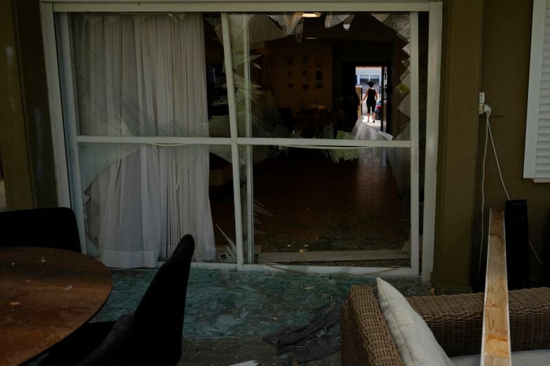 A woman stands on the doorway of a damaged house following an attack from Lebanon, in Acre, north Israel, Sunday, Aug. 25, 2024. (AP Photo/Ariel Schalit)