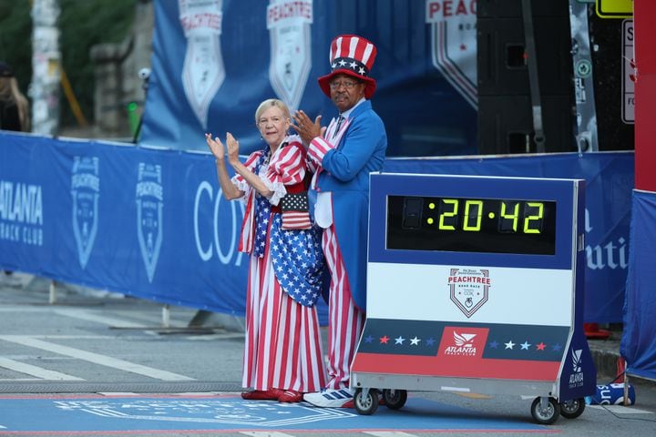 “Uncle Same” and “Betsy Ross” celebrate wheelchair division racers at the finish line of the 55th running of the Atlanta Journal-Constitution Peachtree Road Race in Atlanta on Thursday, July 4, 2024.   (Jason Getz / AJC)
