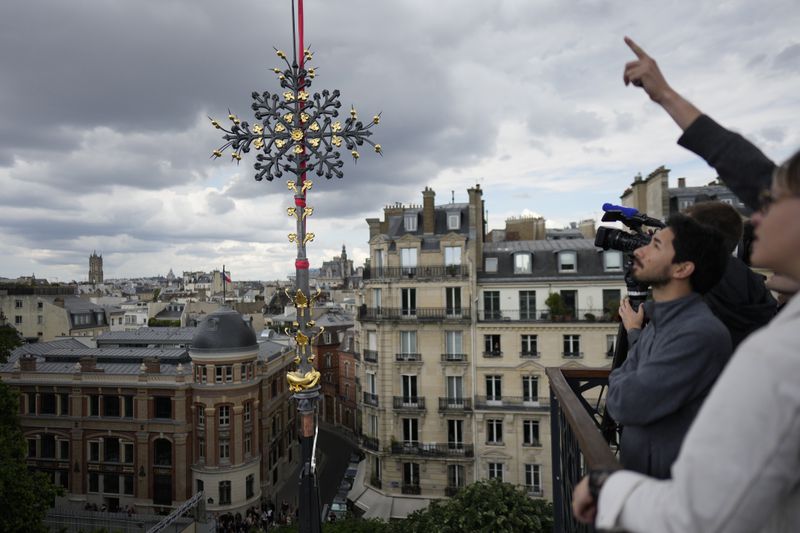 Notre Dame de Paris cathedral's Croix du Chevet is lifted before its reinstallation, Friday, May 24, 2024, in Paris. The Croix du Chevet is the only piece of the cathedral roof that did not burn in the devastating April 2019 fire. (AP Photo/Thibault Camus)