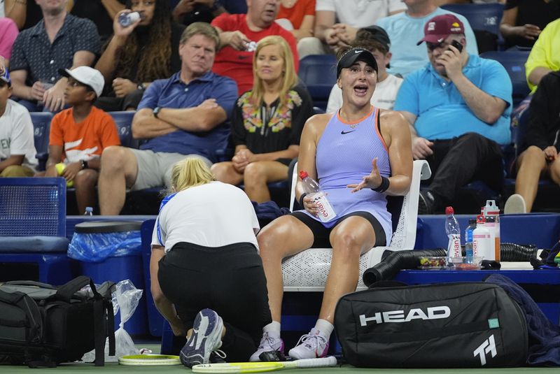 Canada's Bianca Andreescu calls out to her supporters as a trainer works on her leg during a first-round match against Italy's Jasmine Paolini in the U.S. Open tennis championships, Tuesday, Aug. 27, 2024, in New York. (AP Photo/Frank Franklin II)