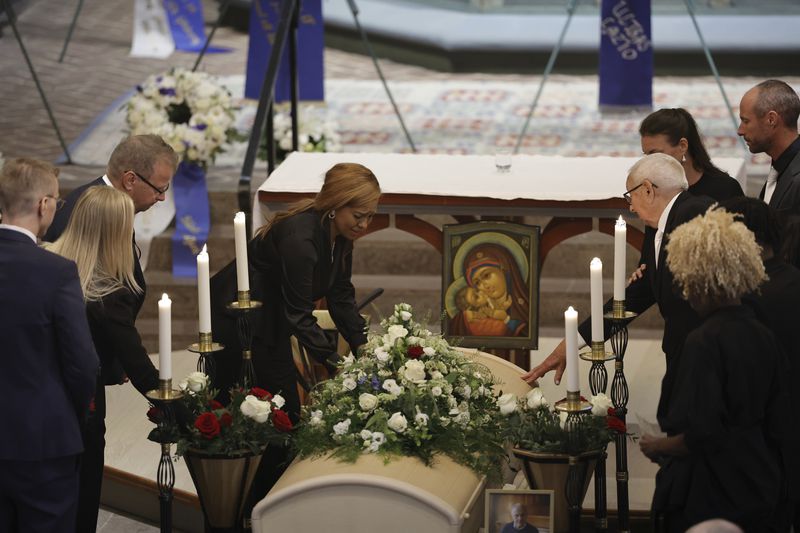 Sven-Goran Eriksson's partner Yaniseth Alcides, left, and his father Sven Eriksson, right, touch his coffin during the funeral service at Fryksände church in Torsby, Sweden, Friday Sept. 13, 2024. (Adam Ihse/TT News Agency via AP)