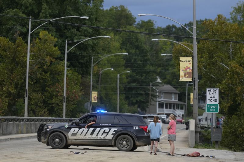 A police car blocks a bridge crossing the Pigeon River in Newport, Tenn., Saturday, Sept. 28, 2024. Tropical depression Helene brought flooding to the area on Friday. (AP Photo/George Walker IV)