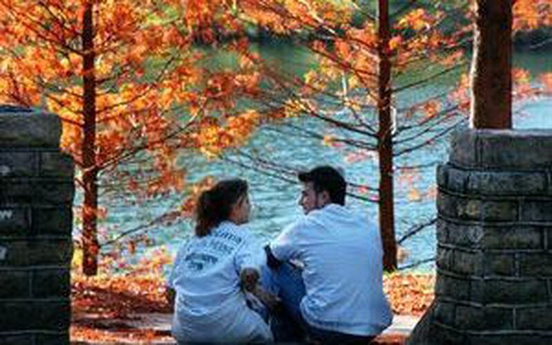 A couple sits amid the fiery fall foliage at Atlanta's Piedmont Park. (AJC file).