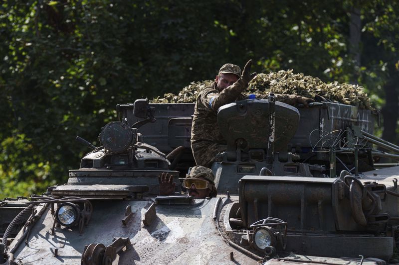 Ukrainian servicemen ride atop on armoured vehicle at the Russian-Ukrainian border in Sumy region, Ukraine, Wednesday, Aug. 14, 2024. (AP Photo/Evgeniy Maloletka)