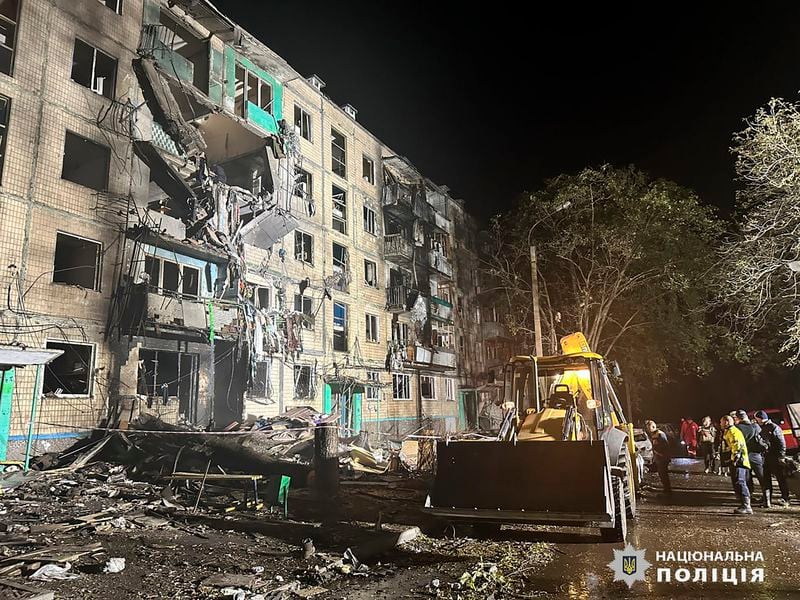 People gather around the damage and debris after a Russian strike on a residential building in Kharkiv, Ukraine, late Wednesday Oct. 2, 2024. (Ukrainian National Police via AP)