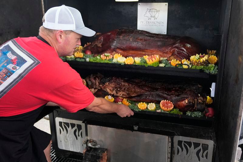 Brent Little of the Pig Diamonds BBQ Team checks on their whole hog entry at the World Championship Barbecue Cooking Contest, Saturday, May 18, 2024, in Memphis, Tenn. (AP Photo/George Walker IV)