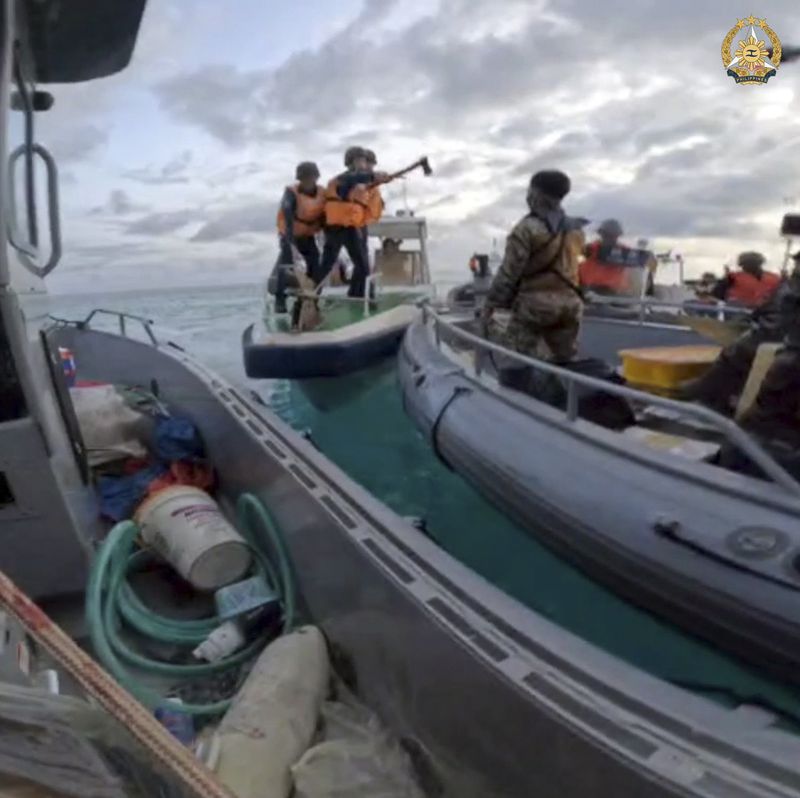 In this handout photo provided by Armed Forces of the Philippines, Chinese Coast Guards hold an axe as they approach Philippine troops on a resupply mission in the Second Thomas Shoal at the disputed South China Sea on June 17, 2024. The Philippine military chief demanded Wednesday that China return several rifles and equipment seized by the Chinese coast guard in a disputed shoal and pay for damage in an assault he likened to an act of piracy in the South China Sea. (Armed Forces of the Philippines via AP)