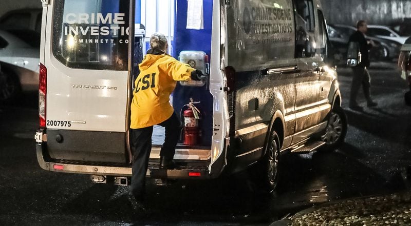 Crime scene investigators collect evidence at the InTown Suites on Stone Mountain Highway, where a woman was found shot dead Tuesday morning. 