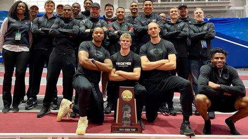 Matthew Boling (center) and fellow gold medalists Karel Tilga (R, on knee) and Kyle Garland pose with their teammates and the NCAA men's indoor third-place trophy this weekend in Fayetteville, Ark. (Photo by UGA Athletics)