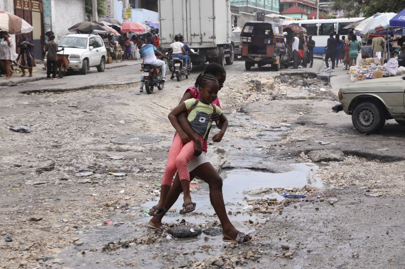 Pedestrians cross a street in downtown Port-au-Prince, Haiti, Monday, Sept. 23, 2024. (AP Photo/Odelyn Joseph)