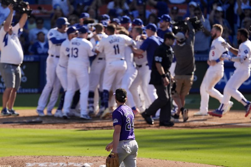 Members of Los Angeles Dodgers celebrate after Mookie Betts hit a walk-off solo home run as Colorado Rockies third baseman Ryan McMahon, below, walks off the field during the ninth inning of a baseball game, Sunday, Sept. 22, 2024, in Los Angeles. The Dodgers won 6-5. (AP Photo/Mark J. Terrill)