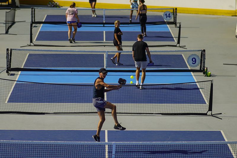 A man jumps to return the ball as people practice pickleball on the courts of CityPickle at Central Park's Wollman Rink, Saturday, Aug. 24, 2024, in New York. (AP Photo/Eduardo Munoz Alvarez)