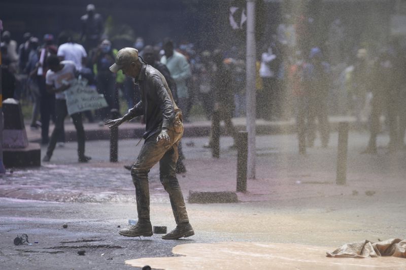 People scatter as Kenya police spray water cannon at them during a protest over proposed tax hikes in a finance bill in downtown Nairobi, Kenya Tuesday, June 25, 2024. (AP Photo/Brian Inganga)