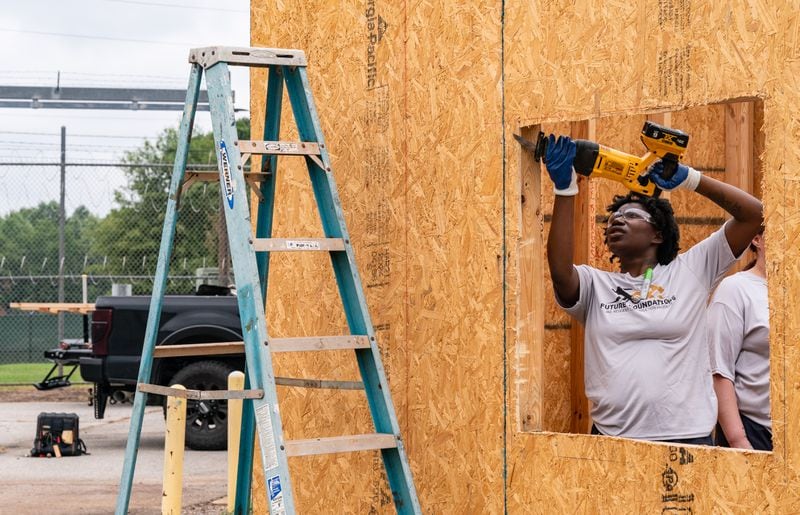 Zykeria Ellis, an inmate at the Athens-Clarke County Jail, uses a saw to shape a window of an incomplete tiny home in the jail yard in Athens, Ga., on Saturday, July 27, 2024. (Seeger Gray / AJC)