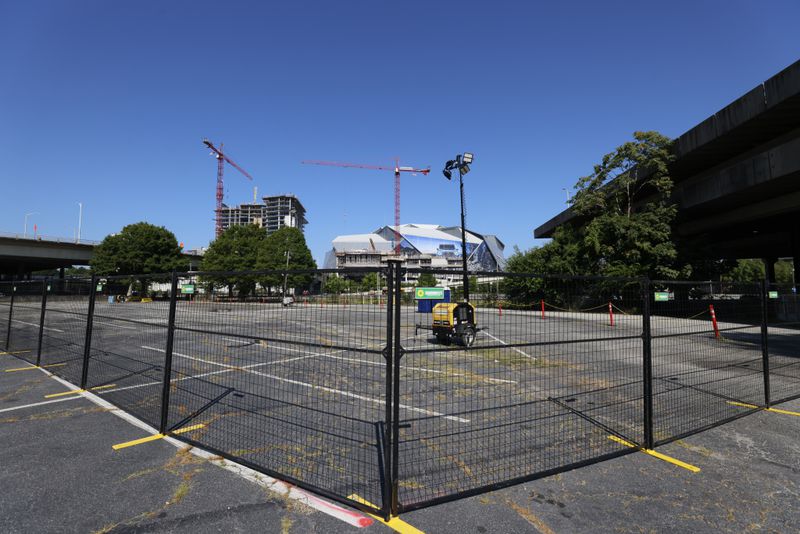 A fence blocks access to the Gulch parking lot as Mercedes-Benz Stadium looms. 
