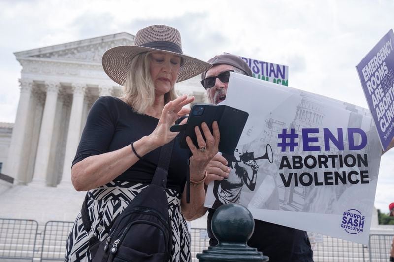 Katie Mahoney, left, and Rev. Patrick Mahoney, chief strategy officer for Stanton Healthcare, an Idaho-based pregnancy center that does not provide abortions, read the text of a Supreme Court decision outside the Supreme Court on Thursday, June 27, 2024, in Washington. The Supreme Court cleared the way Thursday for Idaho hospitals to provide emergency abortions for now in a procedural ruling that left key questions unanswered and could mean the issue ends up before the conservative-majority court again soon. (AP Photo/Mark Schiefelbein)