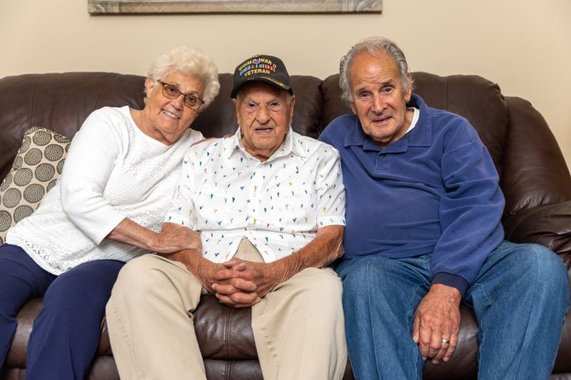 World War II veteran Eugene Russo (center), who turns 100 this month, poses for a portrait with Olga and Nat Galassi, his nephew, at their home in Lawrenceville on Monday, May 13, 2024. (Arvin Temkar / AJC)