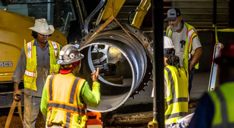 A large 30-inch pipe was seen being lowered into the hole at 11th and West Peachtree Street Tuesday morning, June 4, 2024. According to the city, the Department of Watershed Management was ready to start installing and conducting the remaining steps to restore water service. (John Spink/AJC)