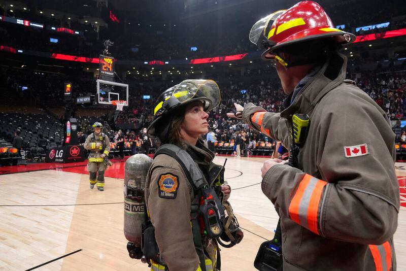 The NBA basketball game between the Toronto Raptors and the Indiana Pacers is suspended as firefighters work to evacuate the building, during the first half Saturday, March 26, 2022, in Toronto. (Frank Gunn/The Canadian Press via AP)