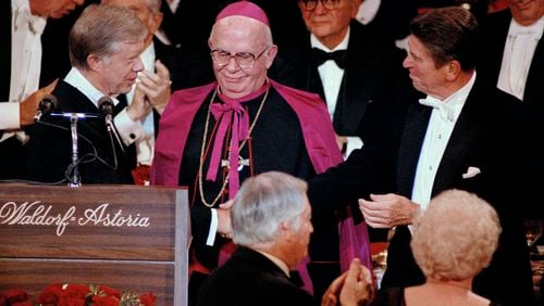 FILE - President Jimmy Carter shakes hands with his rival, Republican presidential nominee Ronald Reagan, at the Al Smith Foundation dinner at the Waldorf-Astoria in New York, Oct. 16, 1980. Archbishop John J. Maguire, center, looks on. (AP Photo/Richard Drew, File)