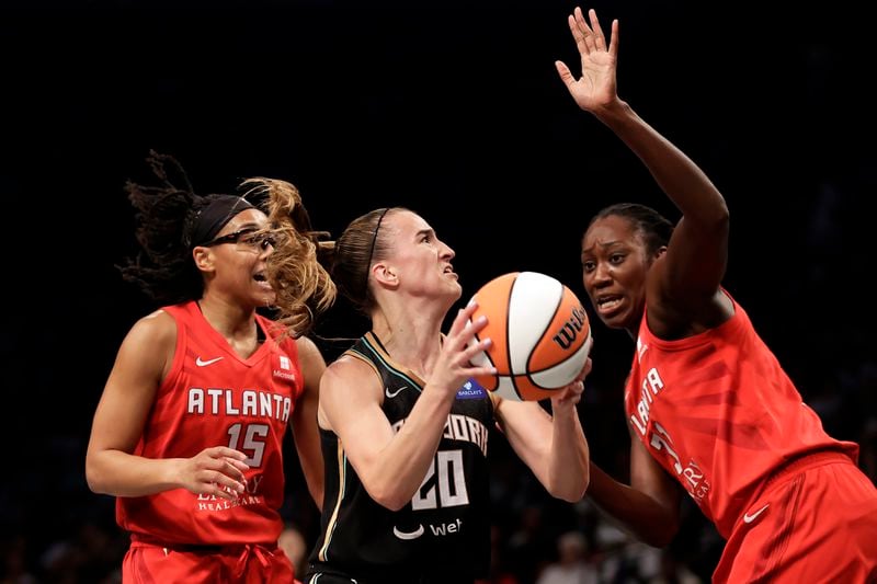 New York Liberty guard Sabrina Ionescu (20) drives to the basket between Atlanta Dream guard Allisha Gray (15) and Tina Charles during the first half of a first-round WNBA basketball playoff game, Tuesday, Sept. 24, 2024, in New York. (AP Photo/Adam Hunger)