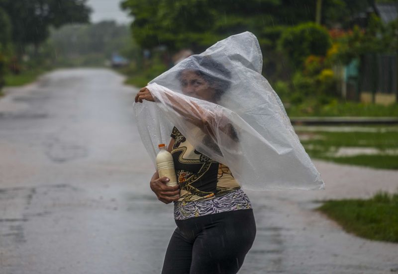 A resident uses a piece of plastic sheet as protection from heavy rains brought on by Hurricane Helene, in Batabano, Cuba, Wednesday, Sept. 25, 2024. (AP Photo/Ramon Espinosa)