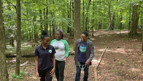 Destinee Whitaker (from left), Quanda Spencer, and Darryl Haddock with the West Atlanta Watershed Alliance walk through the woods at the Outdoor Activity Center, which WAWA operates for the city. (Photo Courtesy of Madeline Thigpen/Capital B)